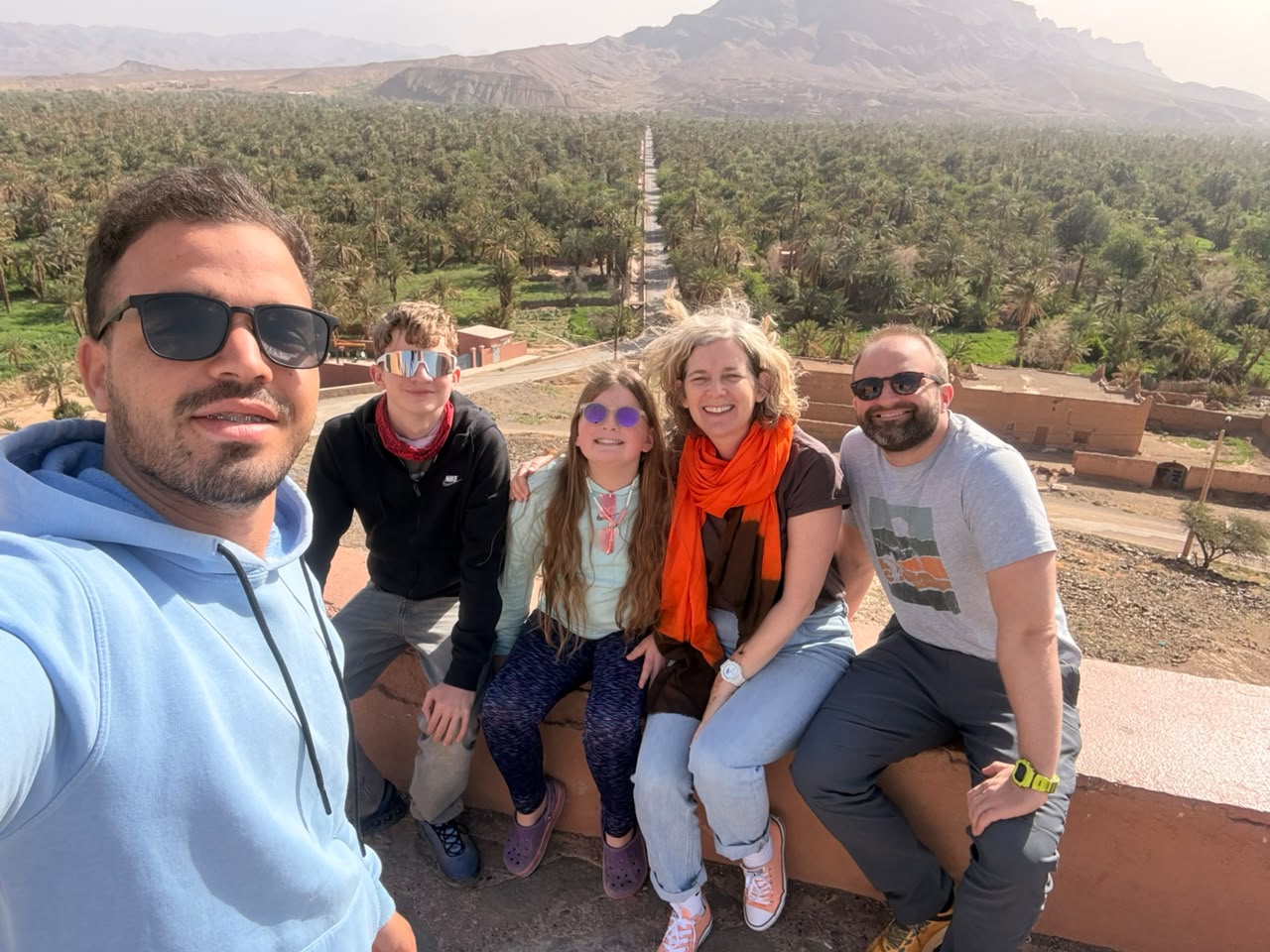 Family enjoying a private Morocco journey with a local guide overlooking a palm oasis
